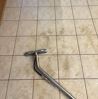 Tile floor being professionally cleaned with wand, showing visible difference between dirty and clea