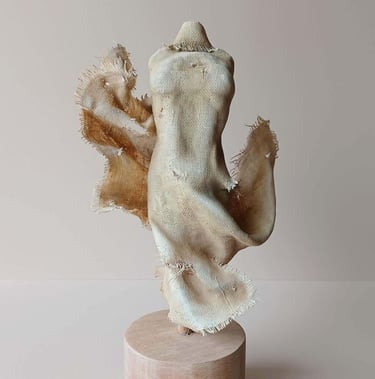 Clay and canvas sculpture of a female torso, wearing windswept, ragged clothes.
