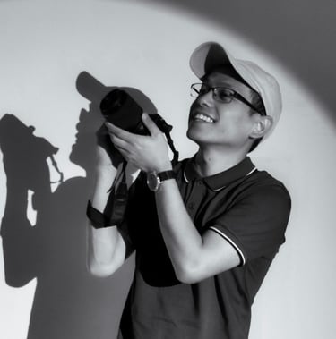 Smiling photographer holding a DSLR camera with a circular spotlight effect and shadow.