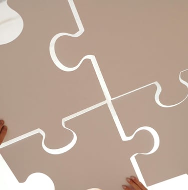 Vier mensen houden grote puzzelstukken samen vast, symbool voor samenwerking en verbinding.