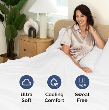 A smiling woman relaxes in luxury white cooling sheets designed for soft, sweat-free sleep comfort.