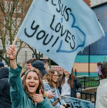 a woman holding a sign that says jesus loves you