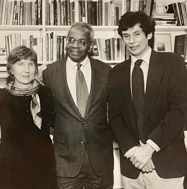 a woman and two men standing in front of a bookcase