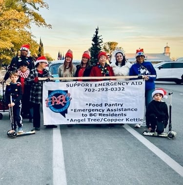 Group of Emergency Aid of Boulder City volunteers dressed for BC Christmas parade with banner