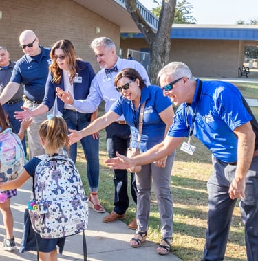 Teachers giving students high-fives as they walk into class