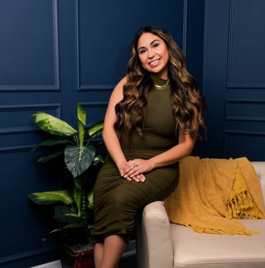 Beautiful Latina sitting on the edge of a comfortable sofa while smiling and crossing her hands