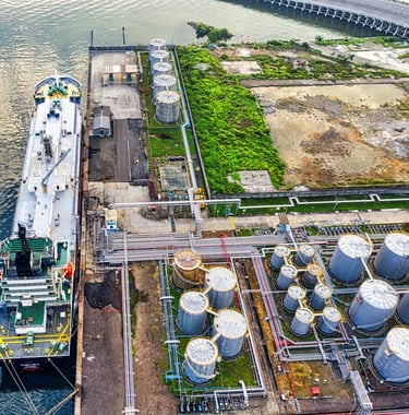a large ship in the water with a large tanks in the background