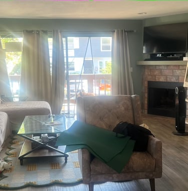before staging: a clutered room with chair, copy table and sofa. fireplace and wood ladder