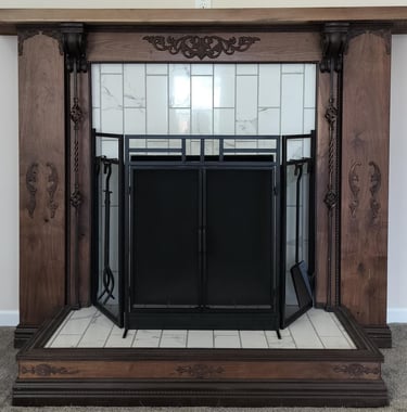 Custom wood fireplace surround with ornate carved detailing and a tiled hearth, featuring a black
