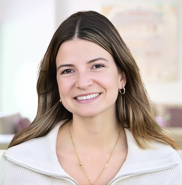 Smiling woman with light brown hair wearing a white sweater and gold jewelry in a professional portrait.