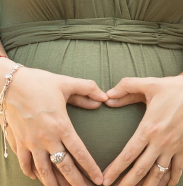 a pregnant woman in a green dress with her hands on her belly
