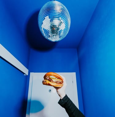 Burger de Flipa sostinguda sota una bola de discoteca en un espai blau, estil original i atrevit