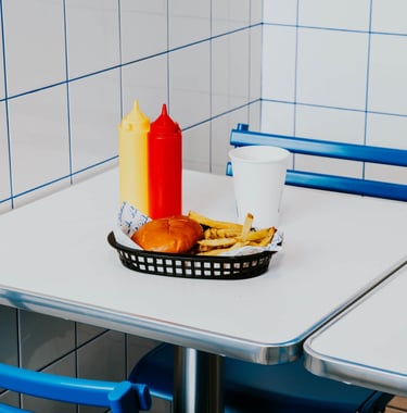 Burger amb patates i salses servides en una taula de Flipa amb estètica minimalista blava i blanca