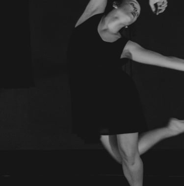 a woman in a black dress is dancing in a black and white photo
