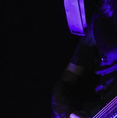 Guitar player in dark atmosphere lit with purple lighting