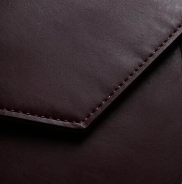Abstract photography of a high-end leather accessory, emphasizing fine craftsmanship and dark, moody textures.