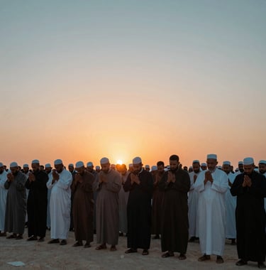 A photography of International / Global Muslim pilgrims standing together in quiet prayer on Mount Arafat at sunset, the sky filled with hues of soft teal and orange.
