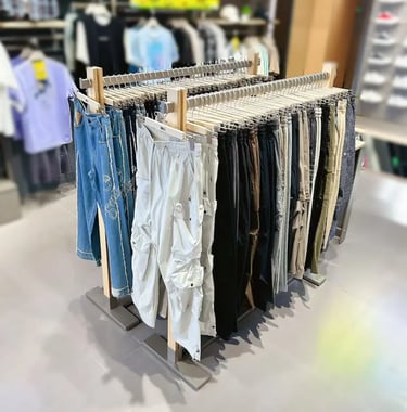 Clothing rack in a retail store displaying an assortment of cargo pants and denim jeans on hangers.