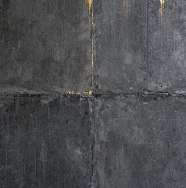 Detail photography of a textured charcoal concrete wall with a subtle golden metallic inlay, high contrast, architectural precision, North American / International setting, soft editorial lighting.