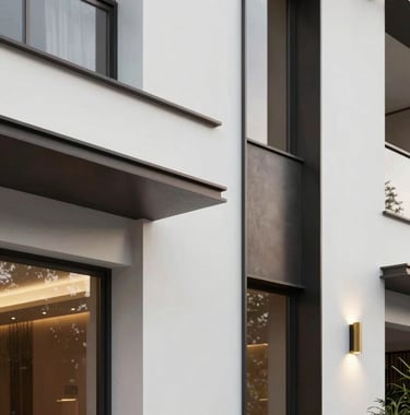 A detail-oriented shot of a luxury property facade in Vargem Grande Paulista. The image showcases clean white walls, dark charcoal metal accents, and a touch of gold from the elegant exterior lighting. Modern South American / Brazilian residential design.