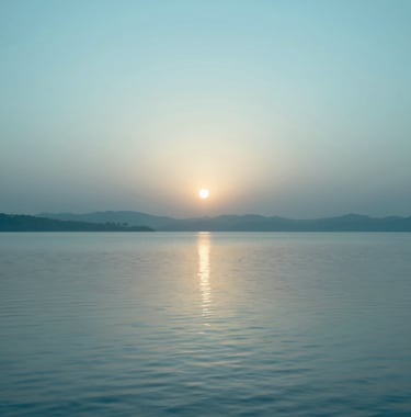 An artistic representation of a sunrise over a calm lake, with ripples moving slowly. The palette uses soft #2E7D8C blues and #F7FCFA highlights. The style is modern, clean, and evokes a sense of spiritual renewal and hope.