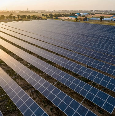 An aerial view of a large-scale commercial solar plant in a rural South Asian landscape, golden hour sunlight hitting the panels, premium professional composition.