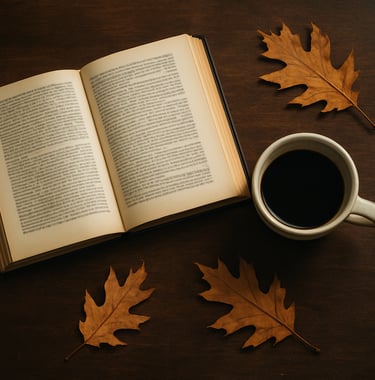 A bird's eye view of a study table in a North American home office featuring an open textbook, a cup of coffee in a ceramic mug, and a few oak leaves. The textures of the parchment paper and the dark coffee brown table are prominent.