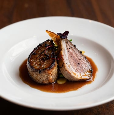 A close-up photograph of a high-end, professionally prepared gourmet dish served in one of Jersey Generations' managed restaurants. The lighting is warm and emphasizes the texture and quality of the food.