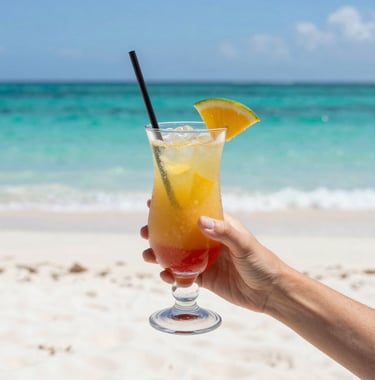 Vibrant and clear photography of a woman's hand holding a tropical drink against a background of white sand and turquoise water, Brazilian style.