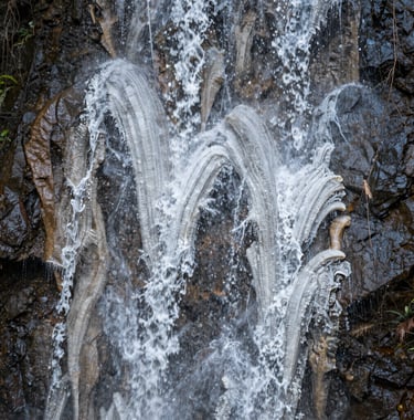 A detailed shot of the intricate textures of the petrified waterfall, showing the layered white mineral formations that resemble frozen liquid. The style is professional nature photography with a focus on natural patterns.