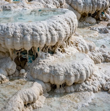 A detailed photograph focusing on the intricate textures of the calcified stone at Hierve el Agua. The off-white mineral deposits form small ridges and valleys, with deep teal shadows emphasizing the age of the formation.