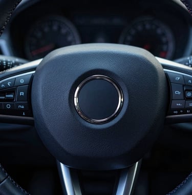 An artistic close-up of a steering wheel's center, featuring a high-end logo. The leather stitching is visible in Soft Frost against the Midnight Navy leather background. The composition is centered and minimalist.