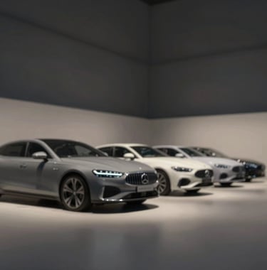 Interior view of a luxury car garage featuring a line of prestige cars under soft, focused spotlights. Minimalist aesthetic, clean lines, dominated by #1A1A1A and #F8F5F0 accents.