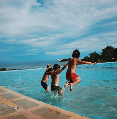 3 kids jumping into a pool. Text reads "family vacays." Linking to a page o family vacation ideas.