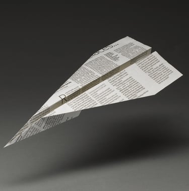 paper plane made of newspaper floating above a grey background