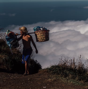 a porter walking up rinjani mountain with food and tant on his back