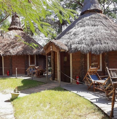 A picturesque view of the Mandina River Lodge, showcasing elegant thatched-roof buildings nestled al