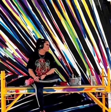 kamile in front of colorful feather mural
