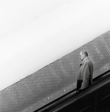 a man in a gray jacket is walking up an escalator in the parisian subway