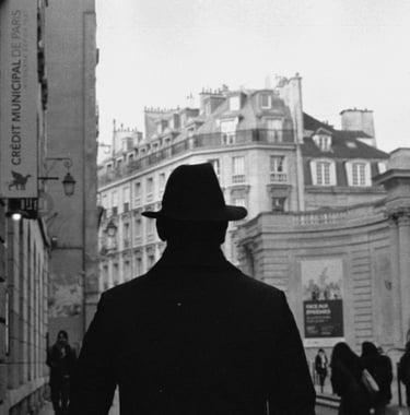 an italian man with a hat and coat walking down a street in Paris