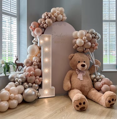 a teddy bear sitting on a table with balloons and balloons
