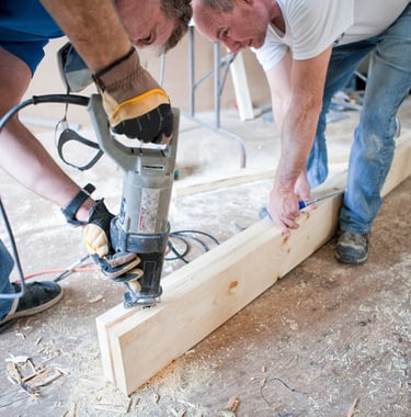 two men cutting a piece of wood