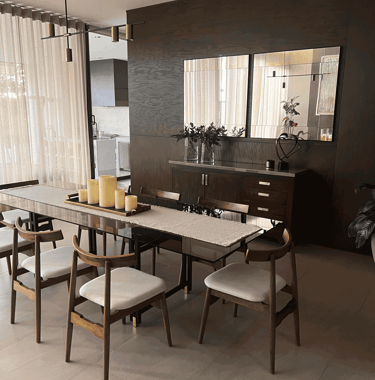 Comedor contemporáneo con muro de madera oscura, velas decorativas y espejo | KARÄNA