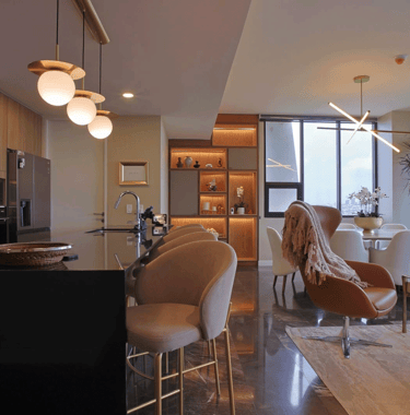 Sala comedor moderno con acabados en mármol, iluminación cálida y mobiliario contemporáneo | KARÄNA