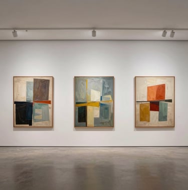 A wide-angle interior shot of a modern gallery in the US. Three large-scale abstract paintings are displayed on a soft white wall with ample white space between them, illuminated by subtle spotlighting.