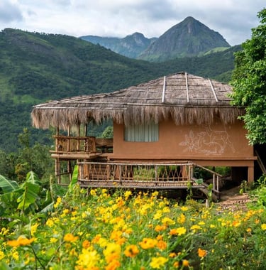 Mud house stay in Kerala with mountains in background.