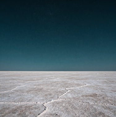 Photography of a dramatic salt flat landscape under a starry night sky, deep teal and off-white tones, high contrast, capturing the vastness and mystery of a Latin American natural wonder.