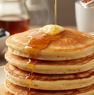 a stack of pancakes with syrup being poured on top of them