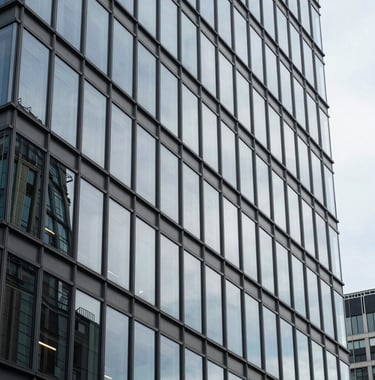 An architectural detail of a modern glass building in La Défense, Paris, reflecting the sky. Sharp lines, professional and forward-thinking corporate atmosphere. European / French style.