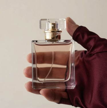 Detail shot of a crystal perfume flacon being held by a hand in a silk sleeve, soft focus, deep burgundy and creamy off-white lighting, high-end fashion photography, European / French style.